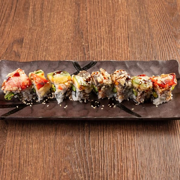 Eight pieces of colorful sushi with various toppings and sauces on a dark rectangular plate.